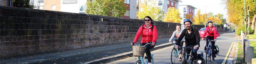 university staff riding bikes in street and smiling at camera